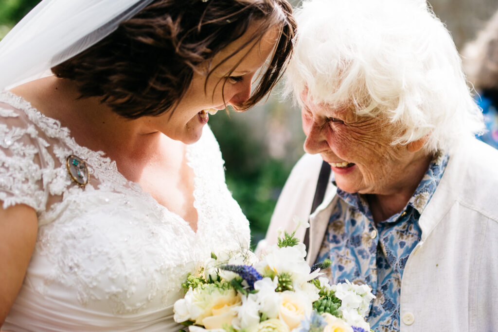 Close up shot of the Bride and Grandmother's head and shoulders after the Wedding Ceremony with summer sunlight highlighting their smiles