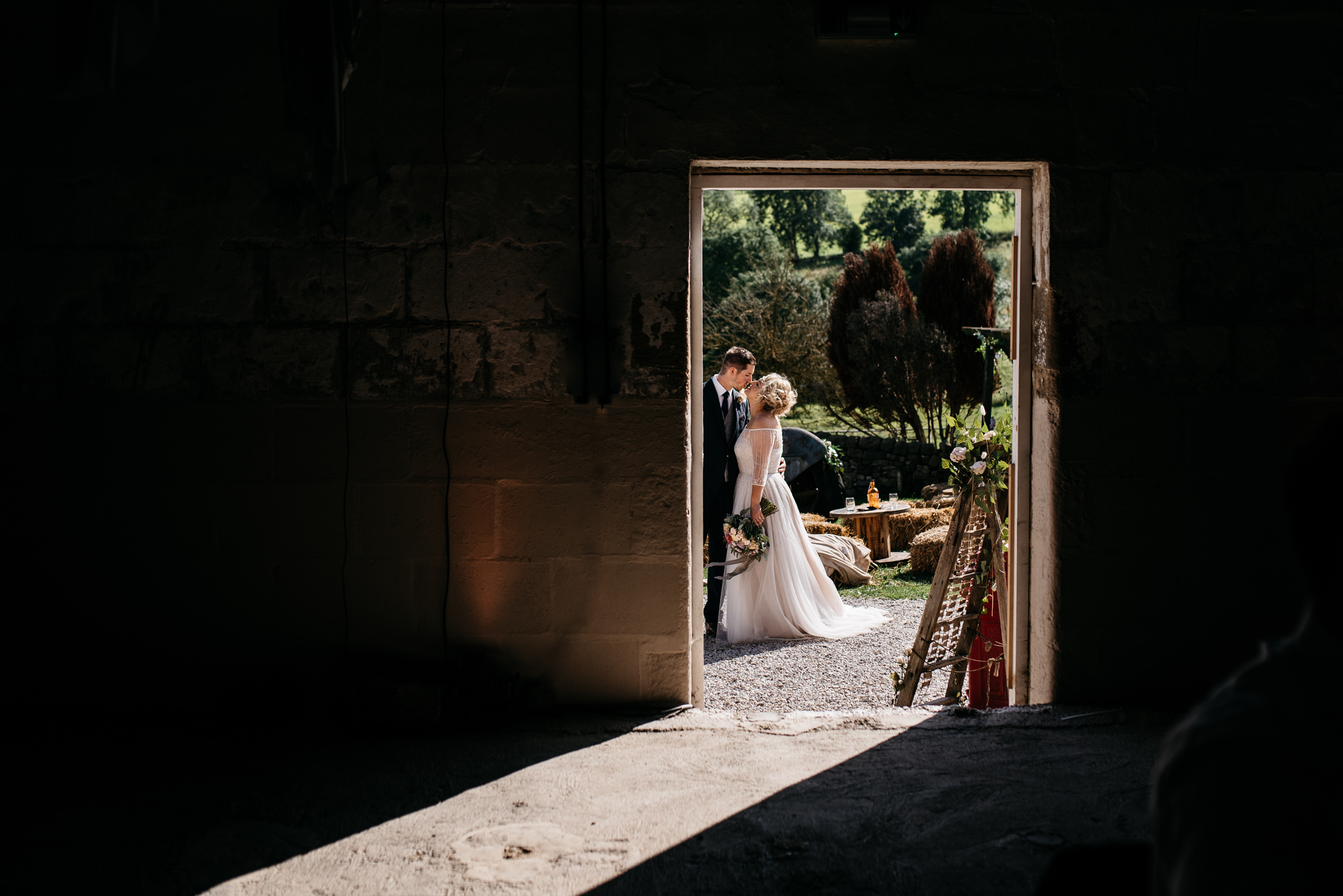Newly married couple, framed in a barn doorway, taking a quiet moment together before being announced in a husband and wife