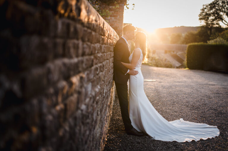 bride and groom lean on an old brick wall at sunset at The Courtyard Venue Oswestry
